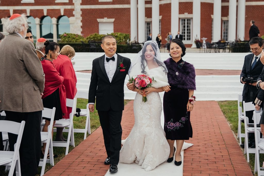 A bride and her parents entering the bride's ceremony at Bourne Mansion wedding