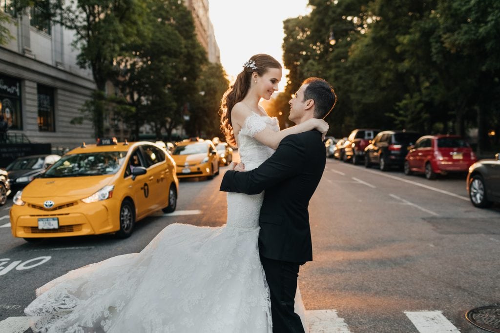 Bride and groom posing on their wedding day near Central Park with yellow taxis on the background