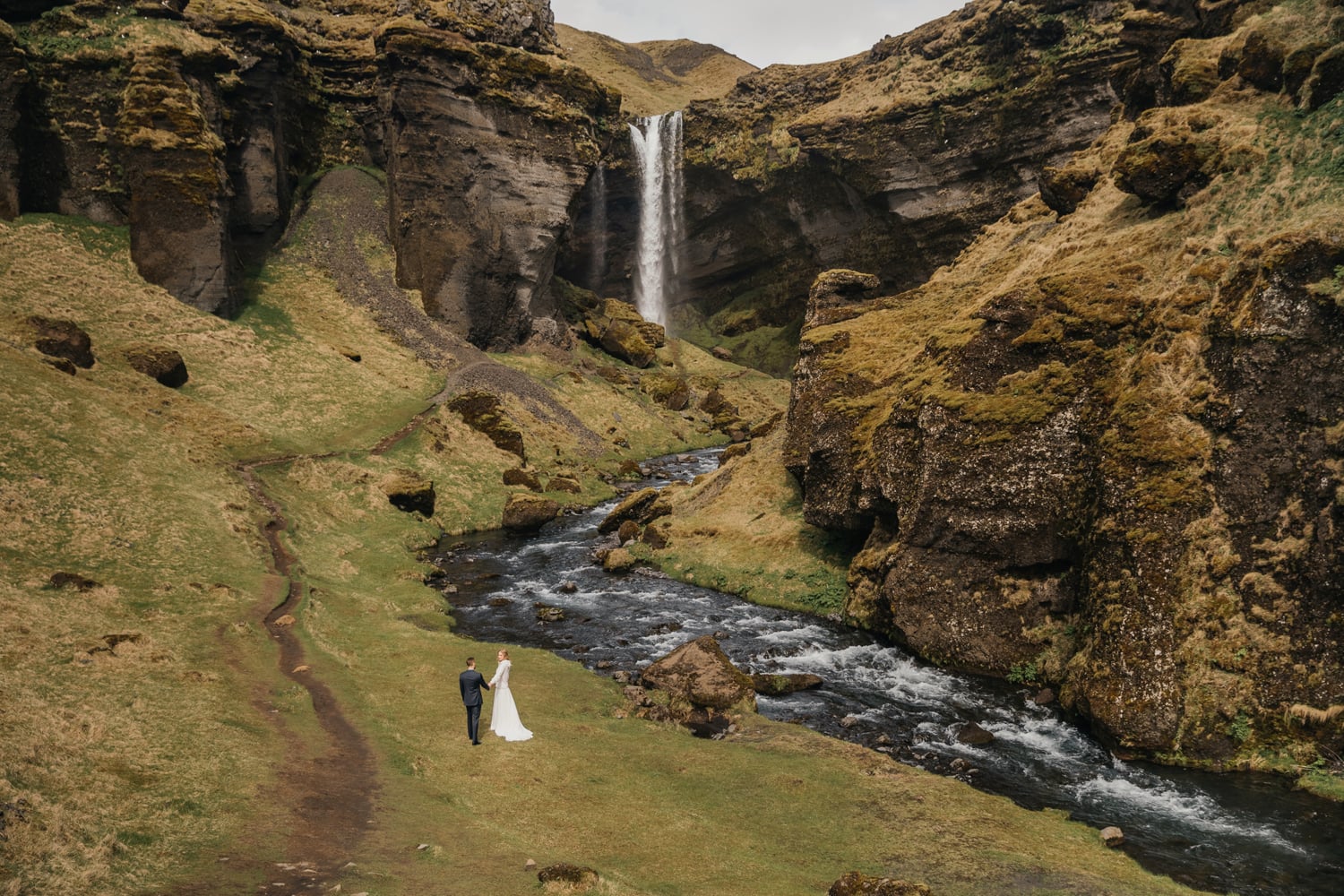 Bride and groom walking to the secret waterfall in Iceland