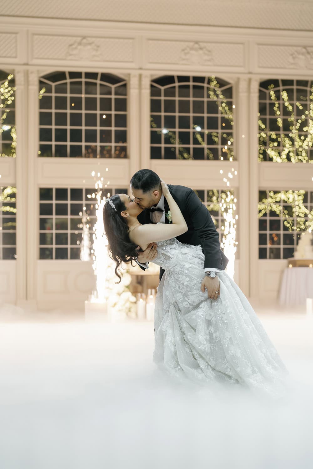 A bride and groom share a romantic first dance at The Estate at Florentine Gardens, surrounded by a dreamy fog effect and sparkling fireworks, creating an unforgettable wedding reception moment.