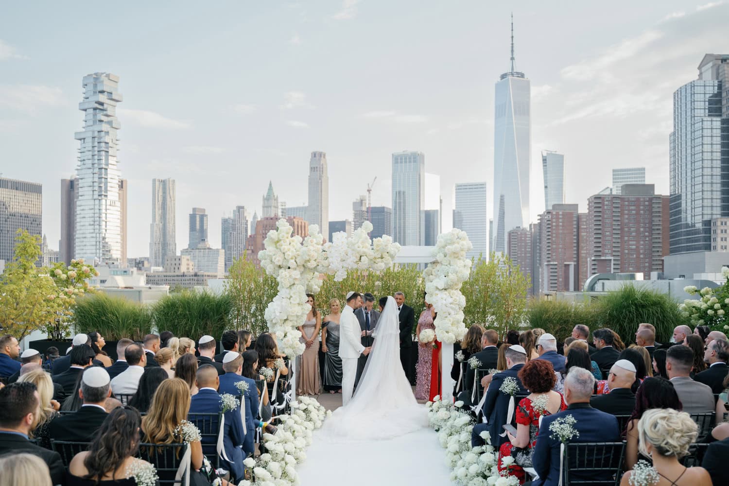 A breathtaking rooftop wedding ceremony at Tribeca Rooftop in NYC, featuring a floral arch, a stunning skyline view of Manhattan, and a romantic setting for an unforgettable celebration.