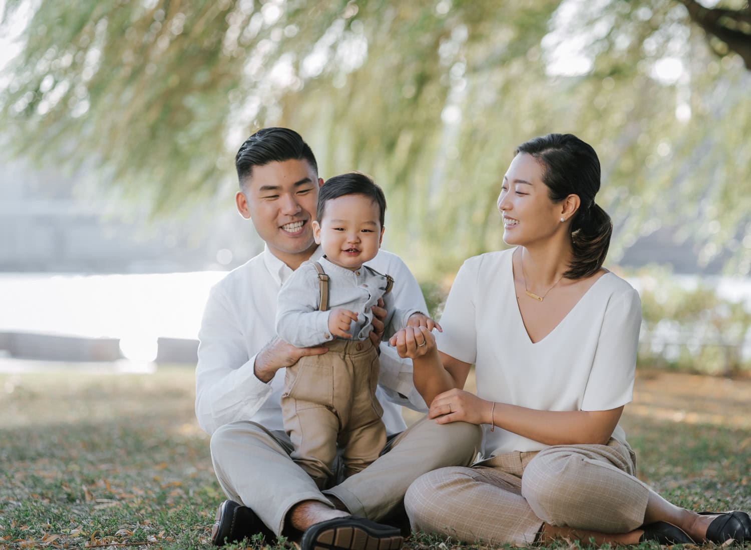 A happy family enjoying a relaxed moment under willow trees by the water, showcasing one of the best locations for family photos in Westchester.