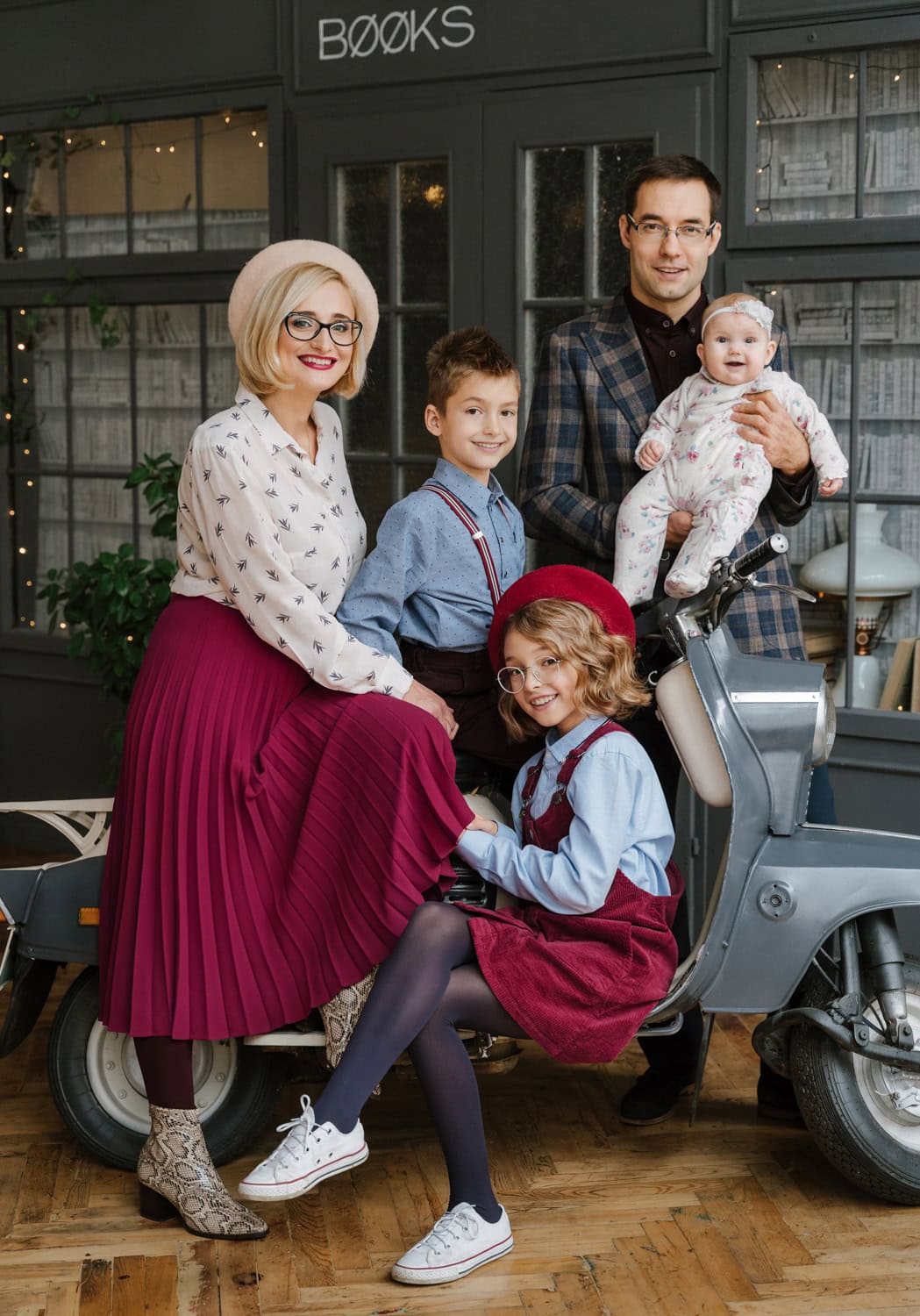 A stylish indoor family portrait session featuring a well-dressed family posing with a vintage scooter.