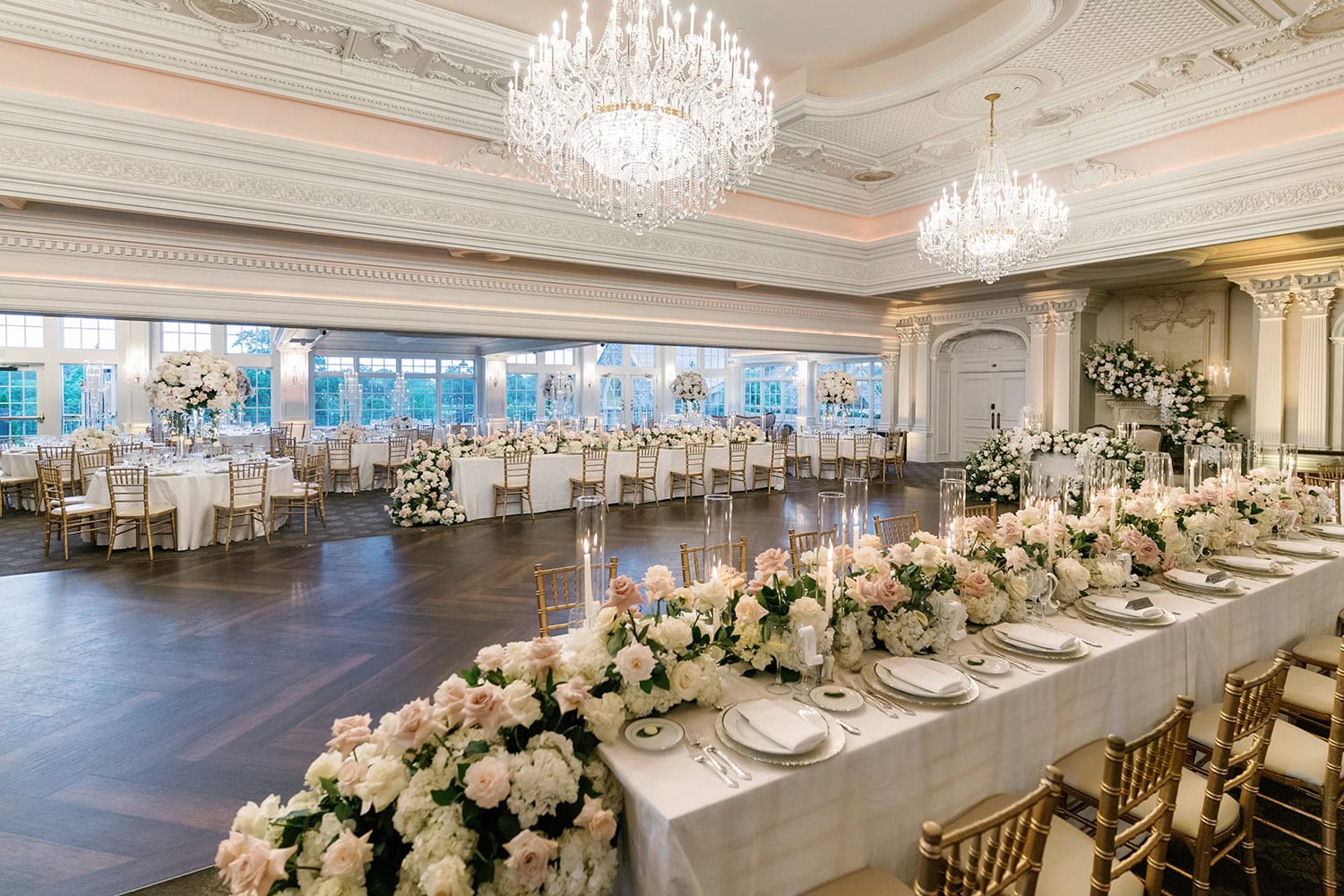 Elegant wedding reception at The Park Savoy in New Jersey, featuring luxurious floral arrangements, gold Chiavari chairs, and crystal chandeliers in a classic ballroom setting.