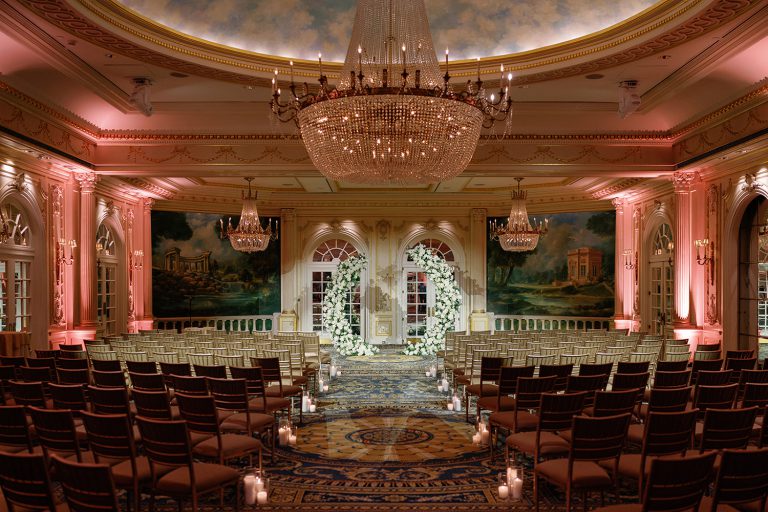 Elegant indoor wedding ceremony setup at JW Marriott Essex House, featuring grand chandeliers, floral arch decorations, and a romantic candlelit aisle.