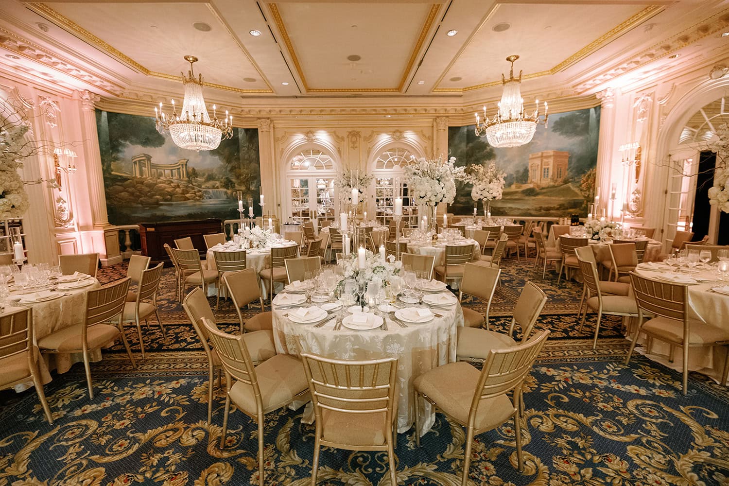 A beautifully set wedding reception at JW Marriott Essex House, featuring grand chandeliers, elegant gold decor, and floral centerpieces in the Grand Salon.