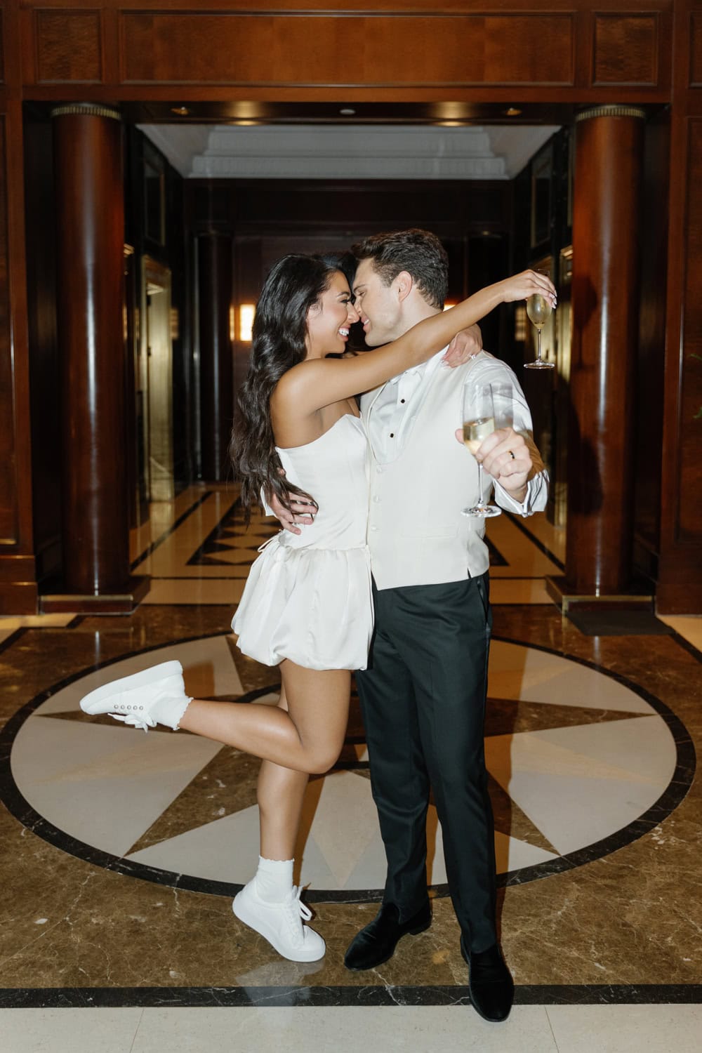 Bride and groom celebrating their wedding afterparty at JW Marriott Essex House, toasting with champagne and embracing in the elegant hotel lobby.