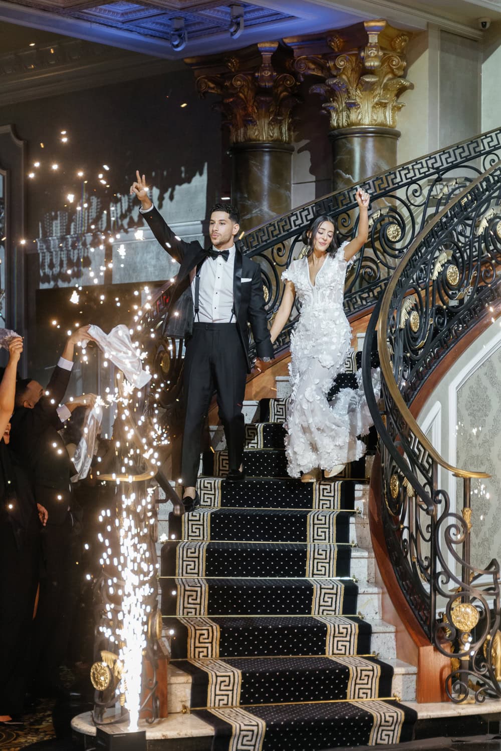 A bride and groom make a grand entrance down The Venetian’s iconic staircase in the Palazzo Ballroom, greeted by cheering guests and dazzling sparklers.