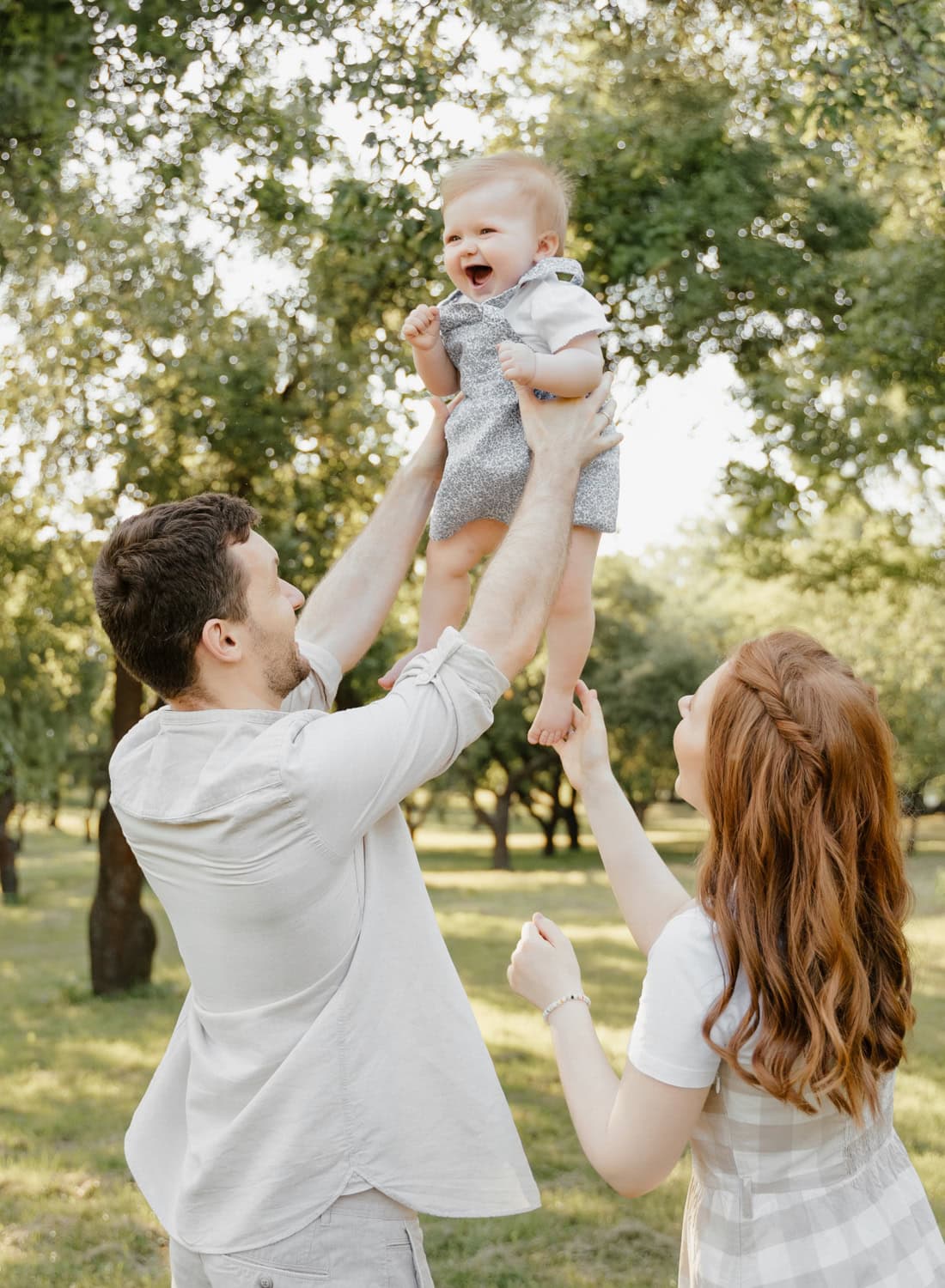 A baby giggles as their parents lift them into the air during a golden-hour family session in Armonk, NY.