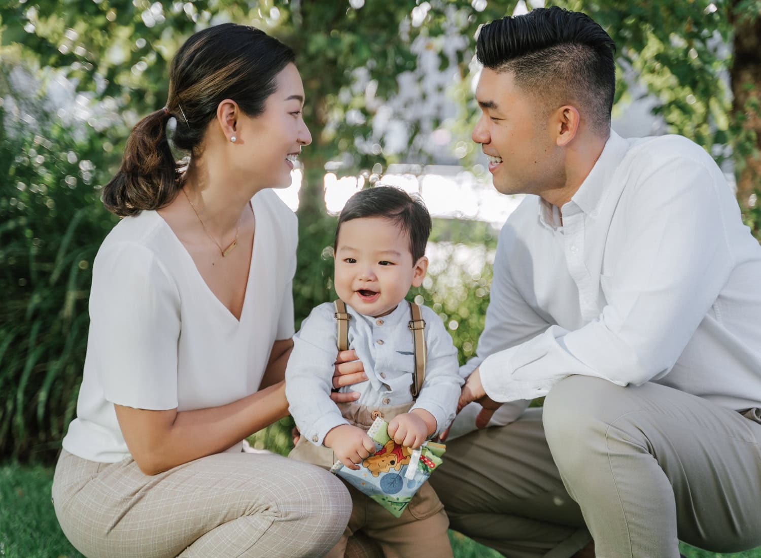 Natural family photography session in Pierson Park, Tarrytown, featuring a joyful baby with parents in a scenic outdoor setting by the water.